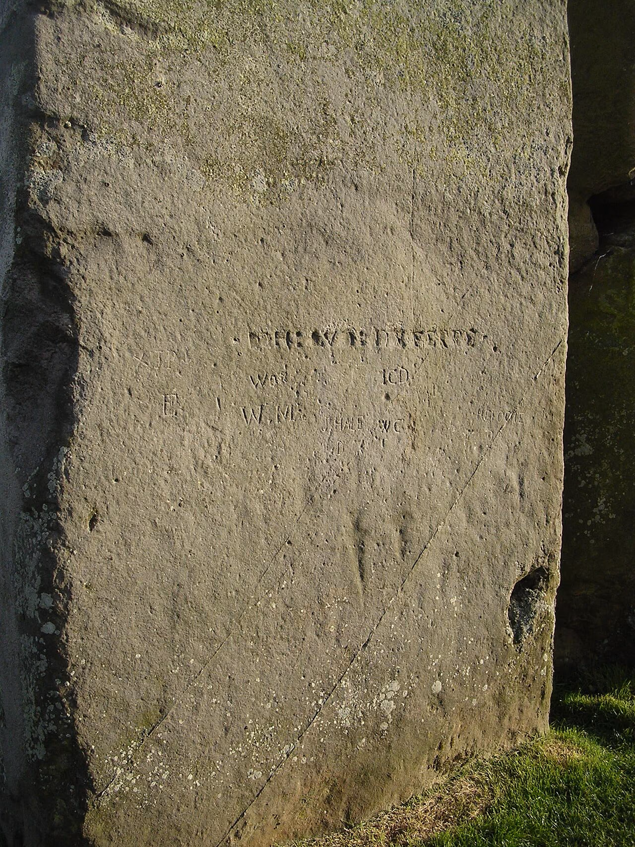Stonehenge sarsen stone with faint ancient axe and dagger carvings visible on the surface.