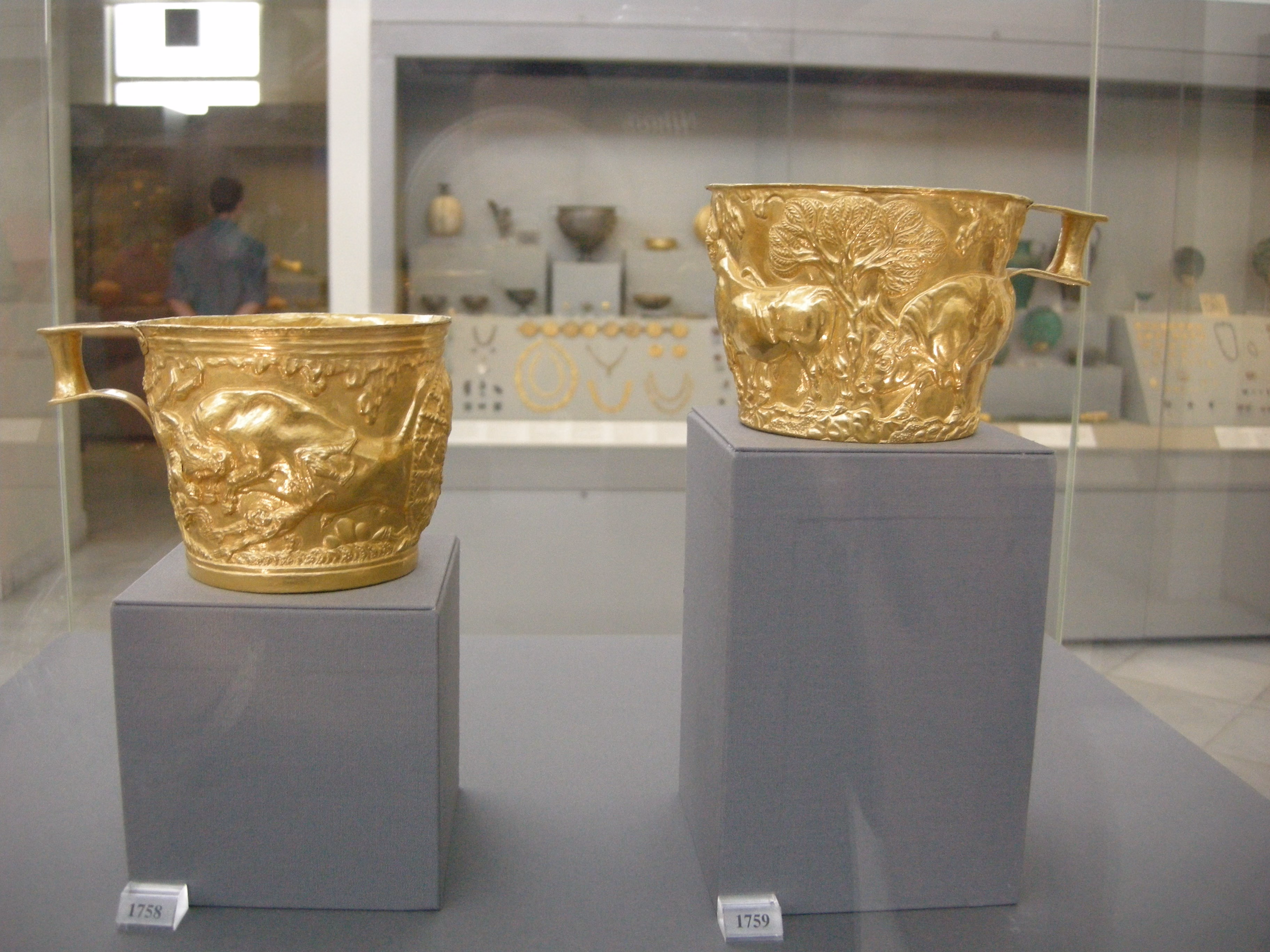 Two ancient gold Vapheio cups displayed in a museum case.